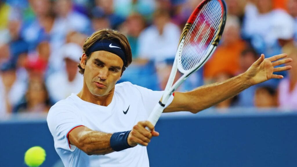 صورة عالية الجودة للاعب التنس الشهير روجر فيدرر وهو يؤدي ضربة خلفية قوية خلال مباراة احترافية. تُظهر الصورة التركيز العالي والمهارات الاستثنائية في التنس.